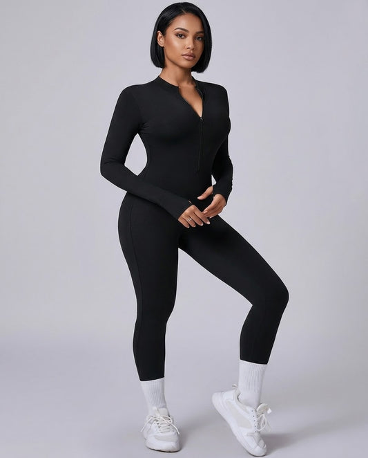A woman modeling a black long-sleeve zip-up bodysuit with a deep V-neckline, paired with white socks and white sneakers, against a solid light gray studio background.