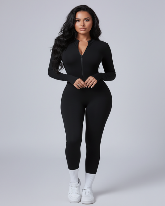 A woman modeling a black long-sleeve zip-front bodysuit with a deep V-neckline, paired with white socks and white sneakers, against a light gray studio background.